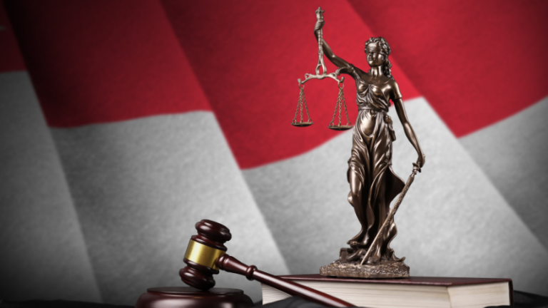 A statue of lady of justice with a gavel and background of Singapore flag.