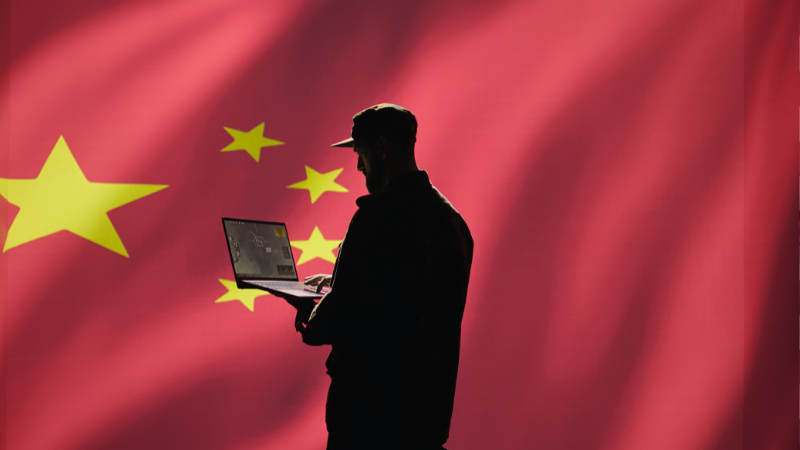 Representation of a man using a laptop with China flag as background