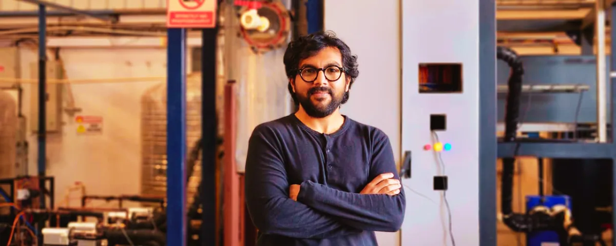 Swapnil Shrivastav, co-founder and CEO of Uravu Labs, stands with arms crossed in front of the company's atmospheric water-generation pilot equipment at its Bengaluru facility.