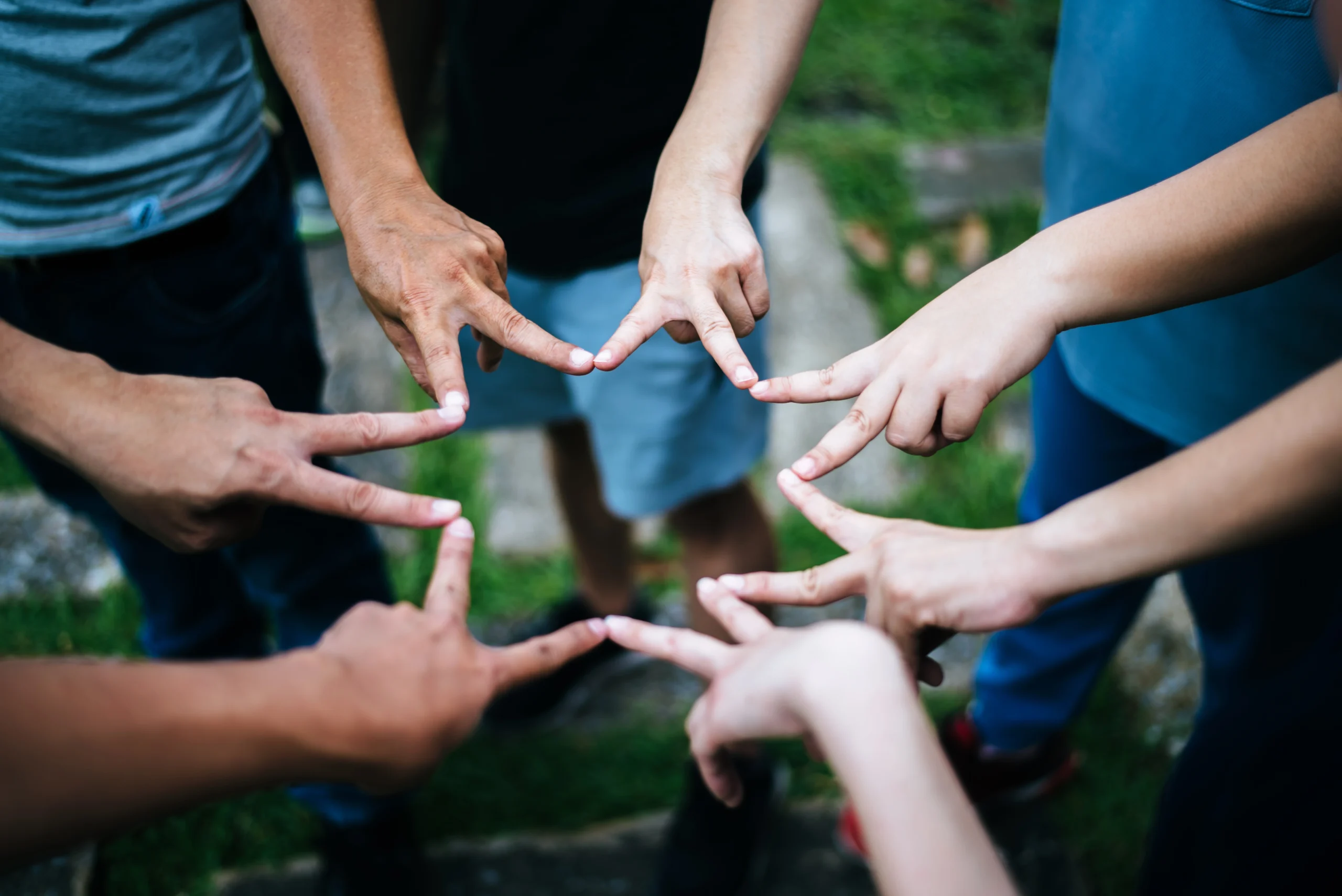 People standing in a circle, joining their fingers to form a star shape.