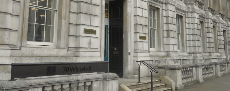 Entrance to the Cabinet Office at 70 Whitehall, London, with a gold "Cabinet Office" nameplate beside the doorway.