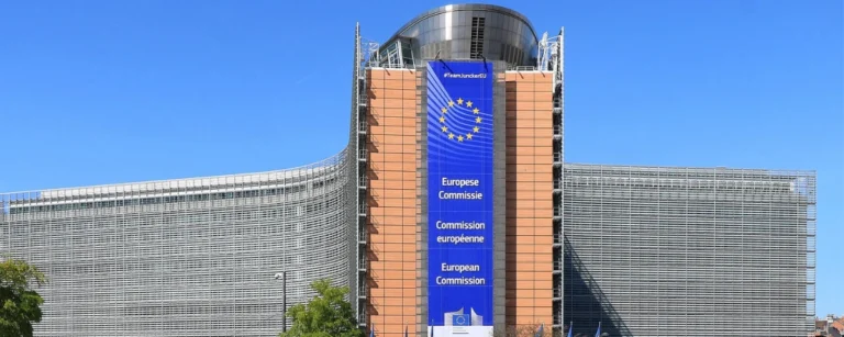 European Union flags outside the European Commission headquarters in Brussels as the Commission publishes AI Act transparency guidelines ahead of their August 2026 implementation.