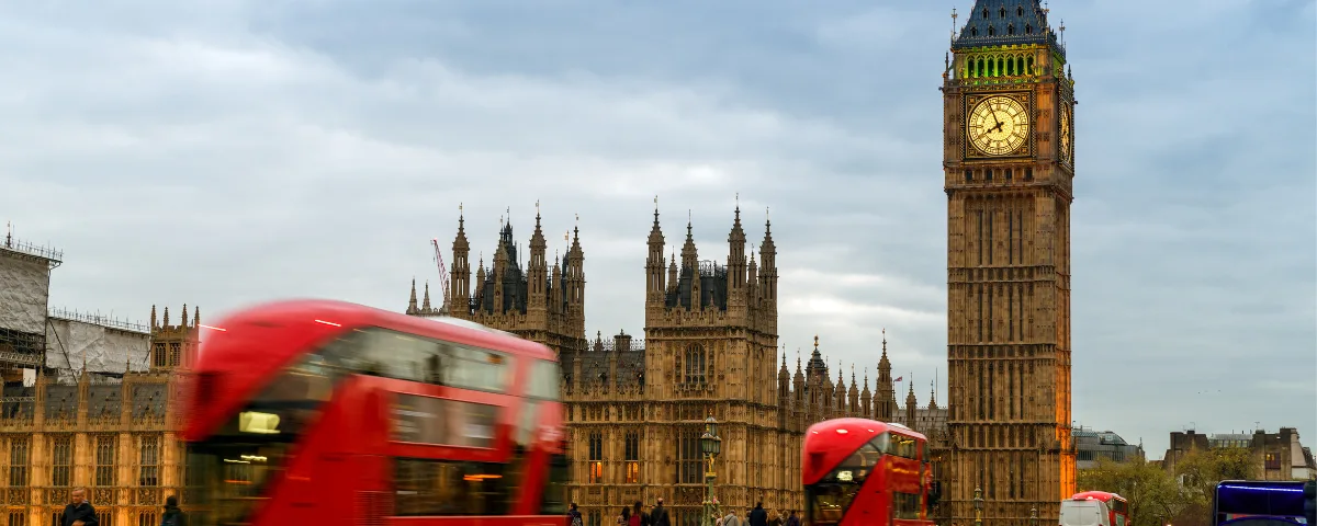 London skyline with Big Ben and Houses of Parliament, red double-decker buses in motion under cloudy sky – UK Global Talent visa expansion announcement.