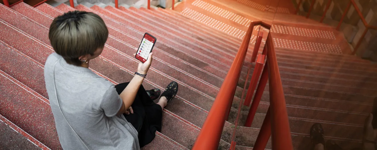 Young person sitting on stairs and looking at a smartphone
