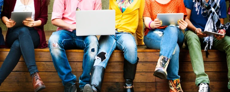 Teen students using laptops during a group study session.