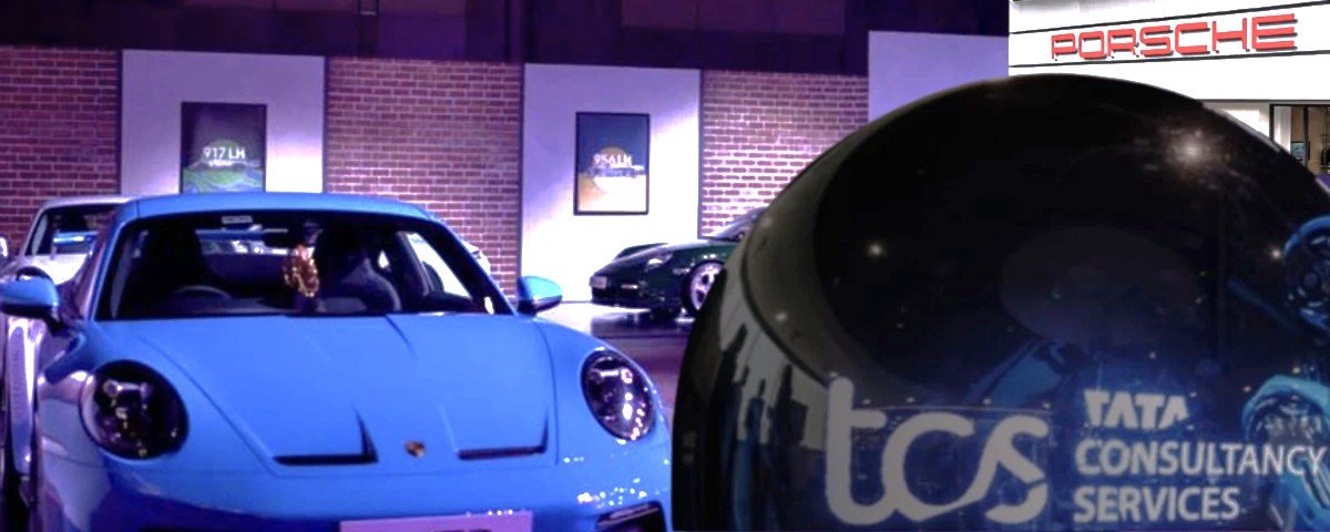 Porsche sports cars displayed at a showroom with the Tata Consultancy Services logo reflected on a foreground vehicle.