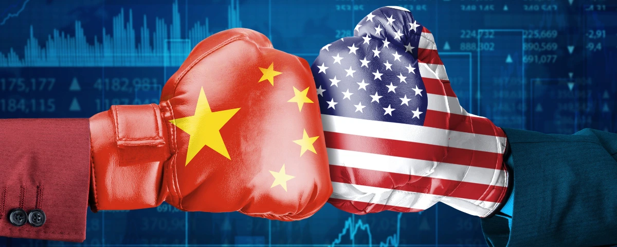 China and US flags on boxing gloves against a backdrop of financial market charts.