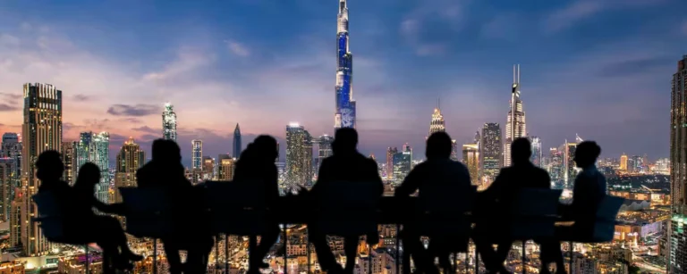 Dubai skyline with Burj Khalifa and silhouettes of business professionals overlooking the city.