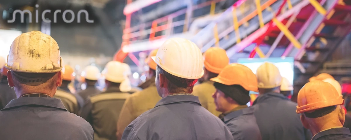 Micron workers wearing hard hats at a semiconductor manufacturing facility.